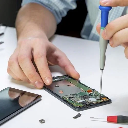 Técnico reparando un celular con un destornillador